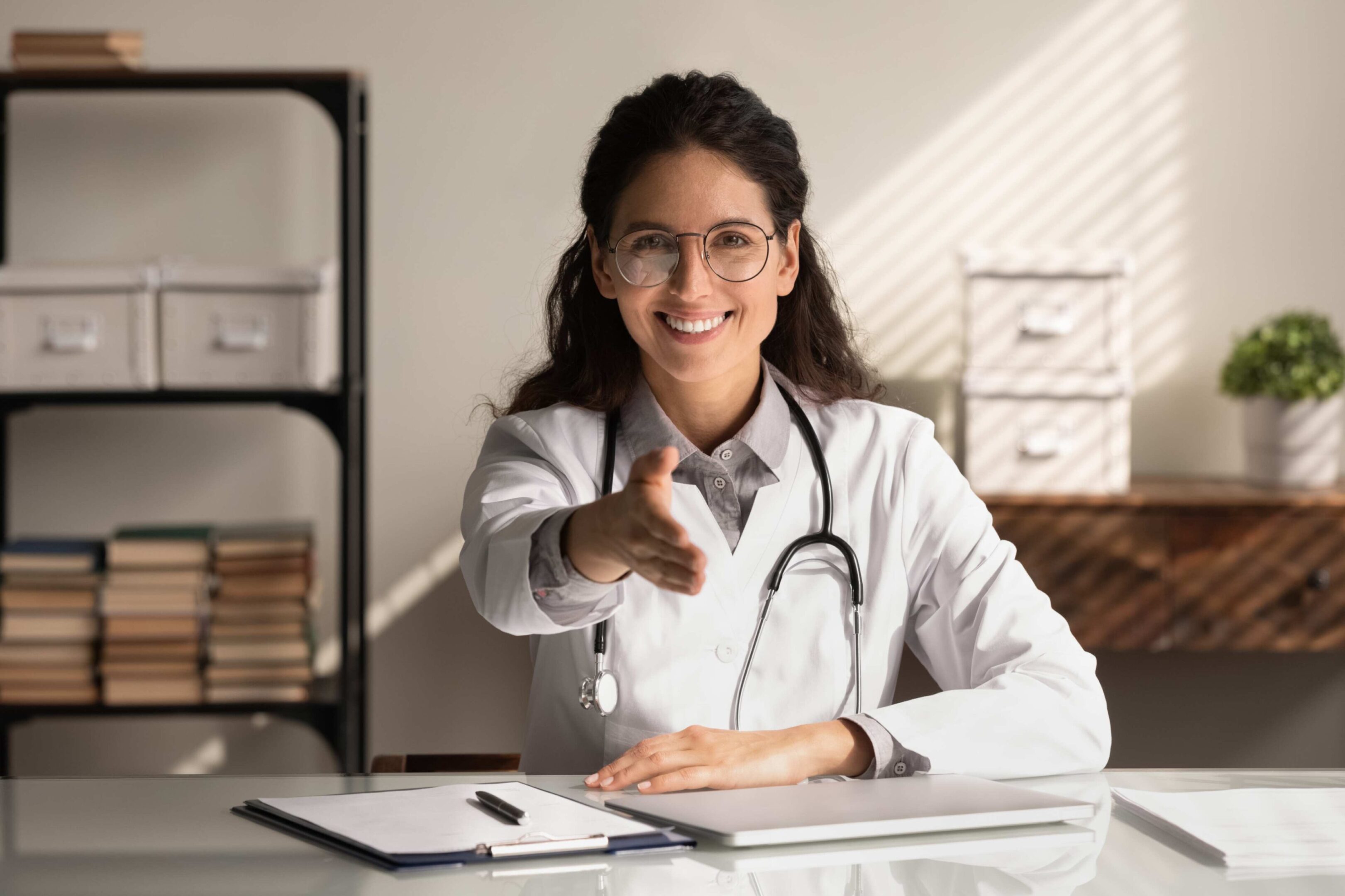 Smiling female doctor offering handshake.
