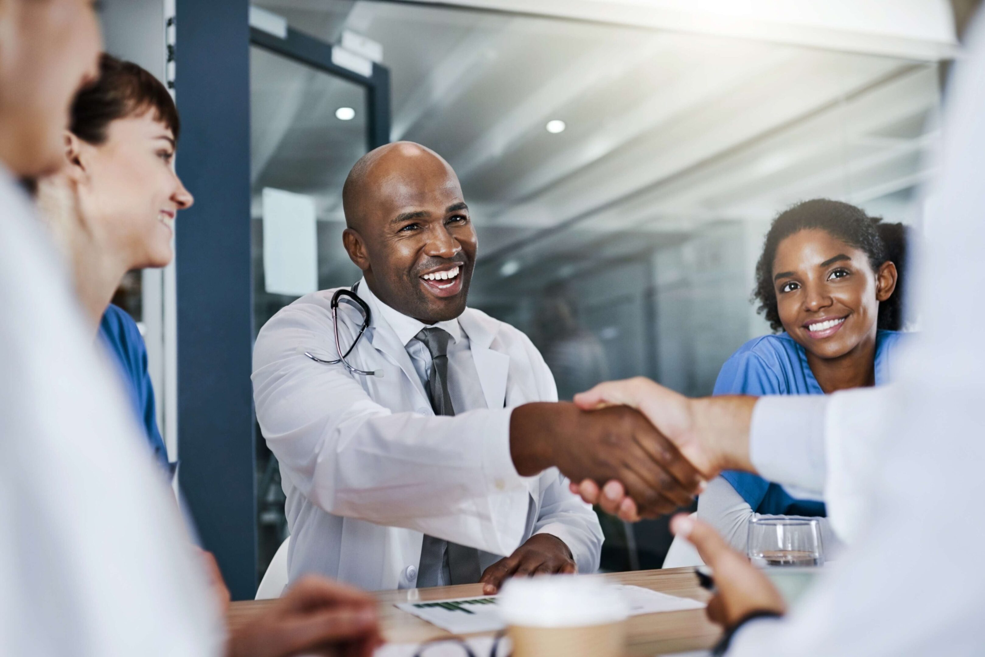 Smiling doctors shaking hands in meeting.