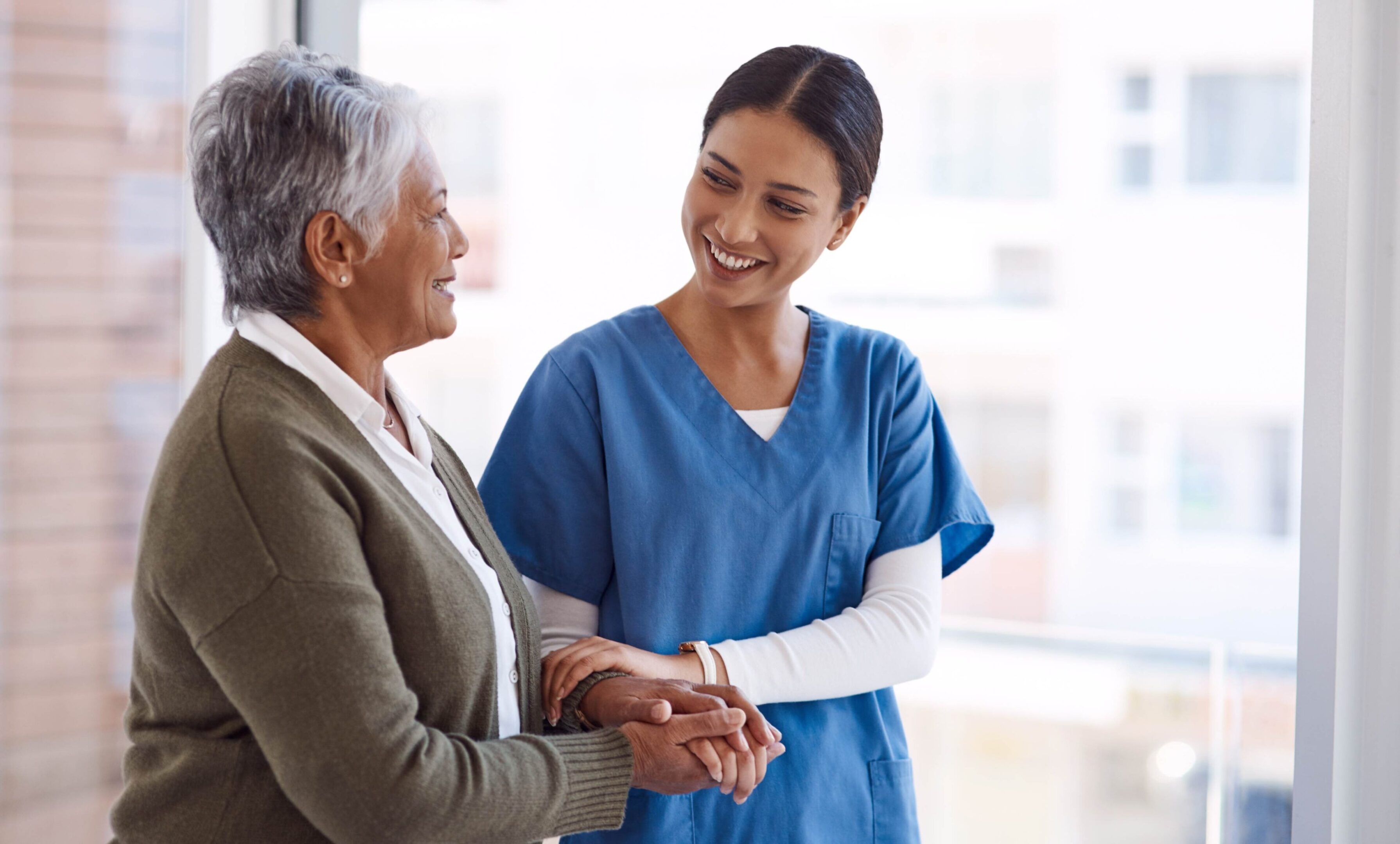 Nurse and elderly patient holding hands.
