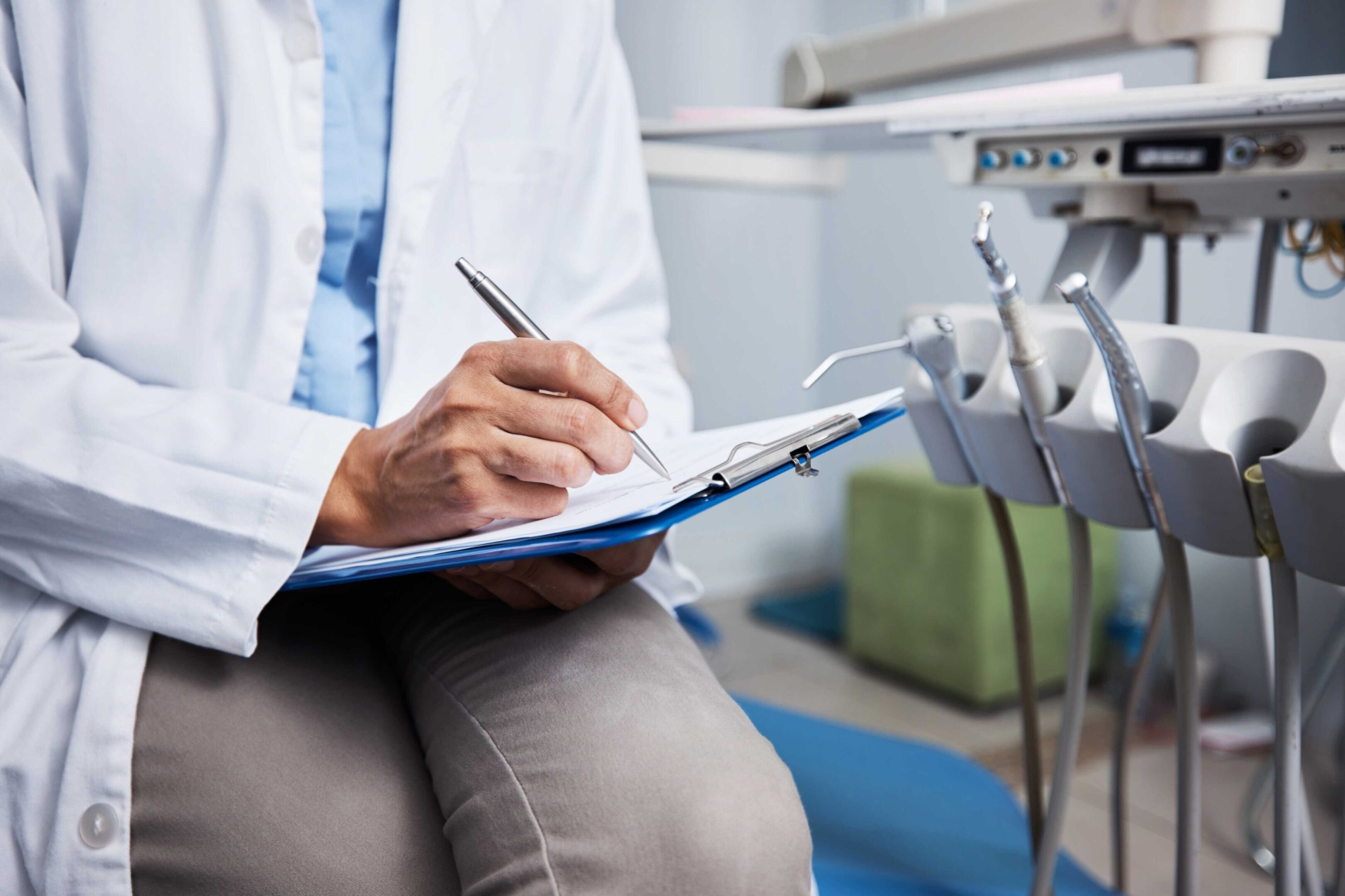 Dentist writing notes on clipboard.